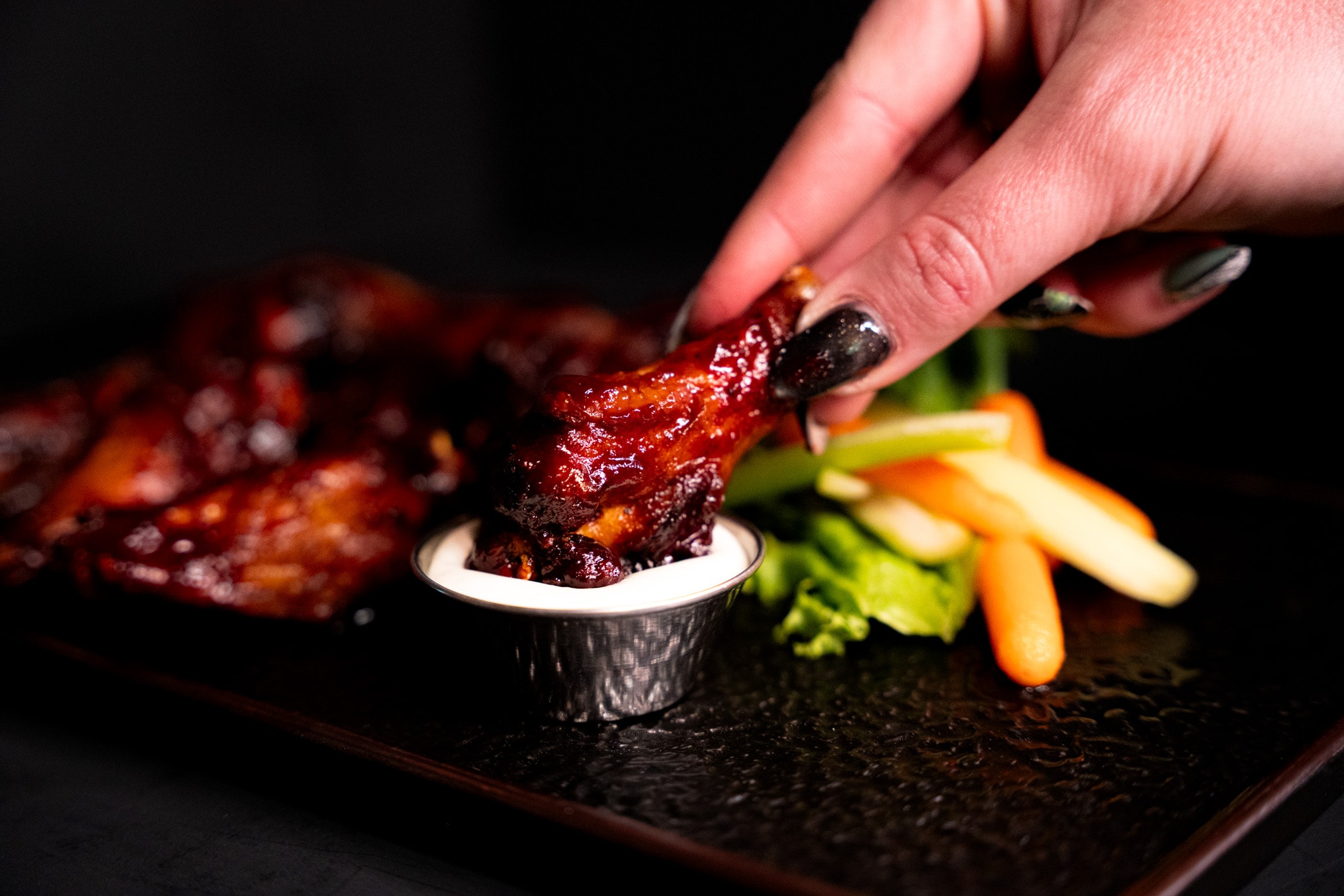 Glazed chicken wing dipped in sauce