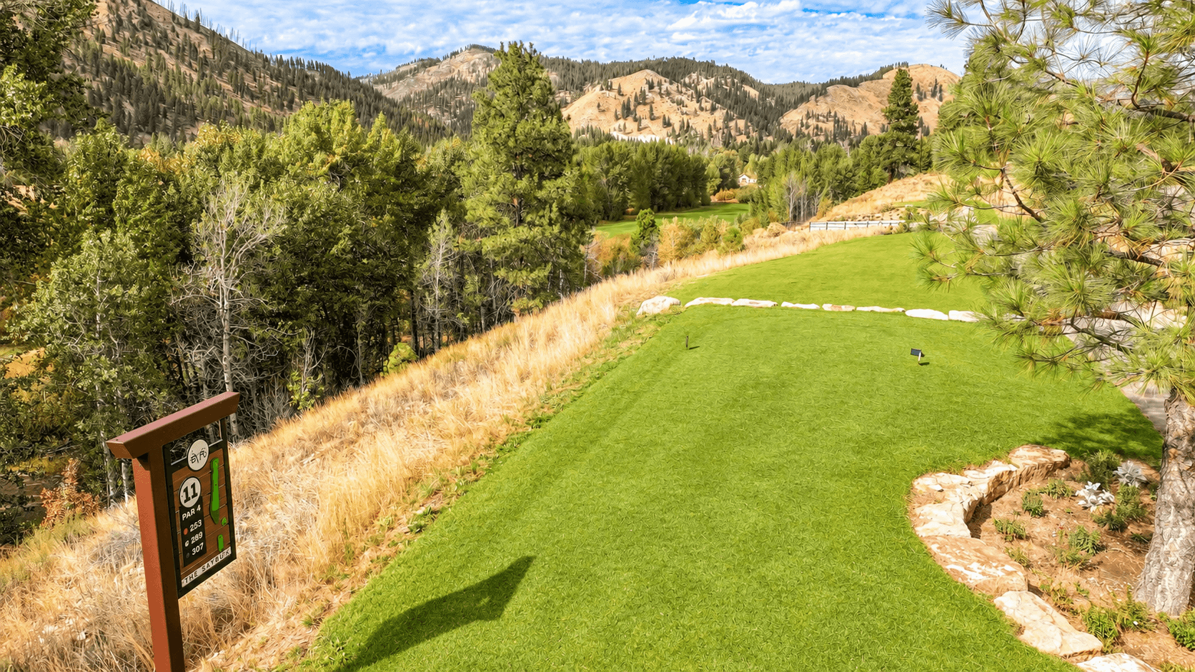 Aerial view of a golf hole beside a rocky slope